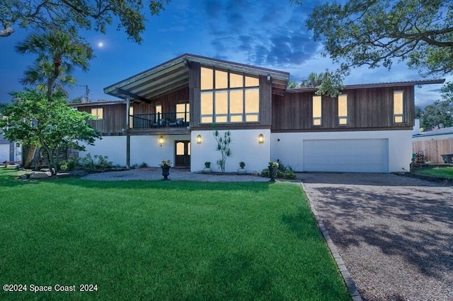 modern home with a garage, a yard, and a balcony