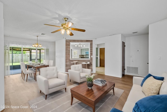 living room with a textured ceiling, ceiling fan with notable chandelier, and hardwood / wood-style flooring