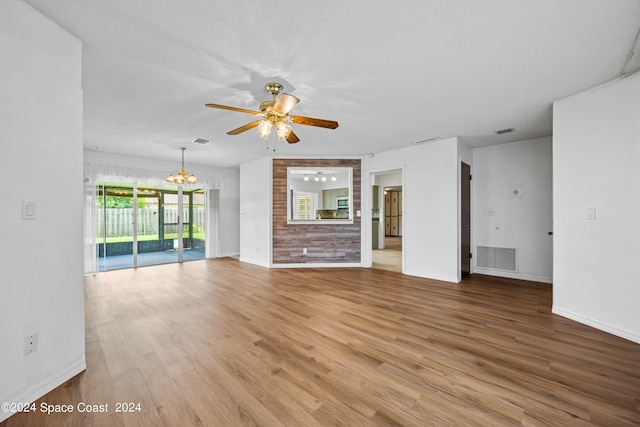 unfurnished living room featuring light wood-type flooring, a textured ceiling, and ceiling fan with notable chandelier