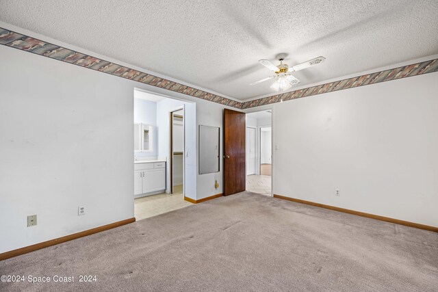 unfurnished bedroom with light carpet, a textured ceiling, ensuite bath, and ceiling fan