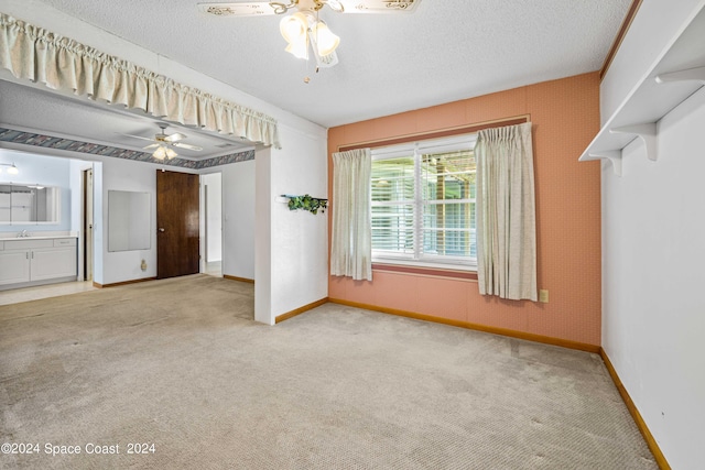 unfurnished room with light carpet, a textured ceiling, sink, and ceiling fan