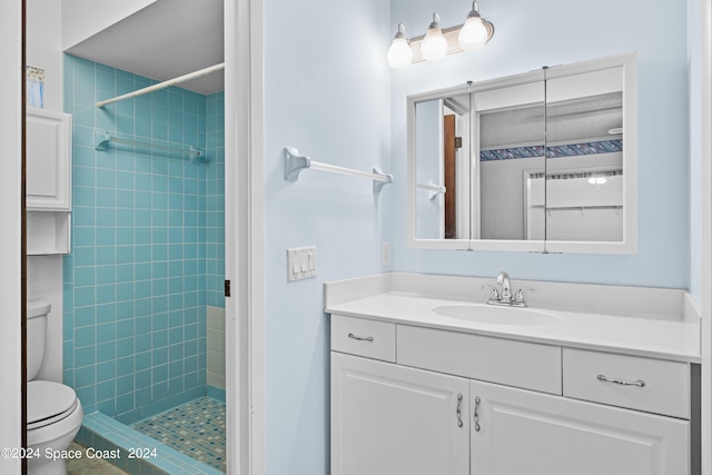 bathroom with tiled shower, toilet, and vanity