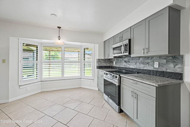 kitchen with tasteful backsplash, appliances with stainless steel finishes, gray cabinetry, light stone counters, and light tile patterned floors