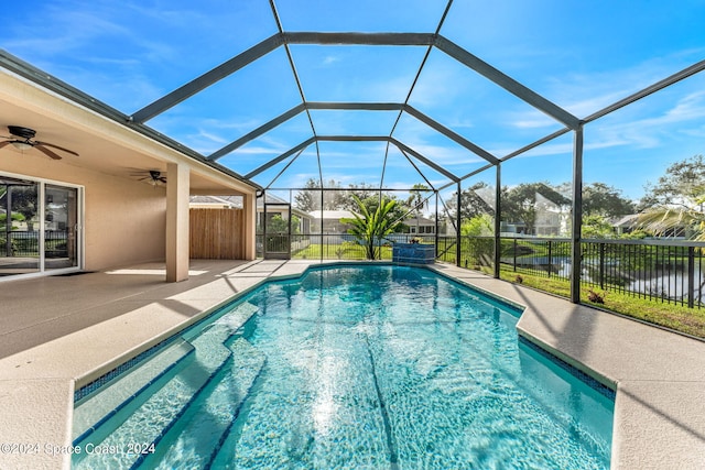 view of pool featuring a patio area, a water view, ceiling fan, and glass enclosure