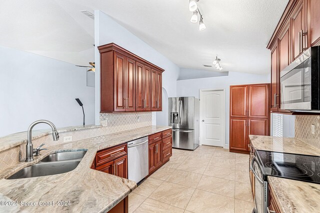 kitchen with lofted ceiling, sink, appliances with stainless steel finishes, backsplash, and light stone counters