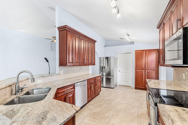 kitchen with sink, appliances with stainless steel finishes, backsplash, light stone counters, and vaulted ceiling