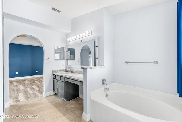 bathroom featuring vanity and tiled bath