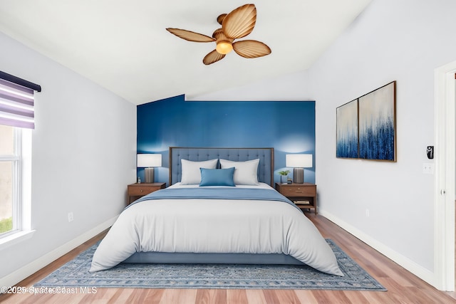 bedroom with ceiling fan, lofted ceiling, and wood-type flooring