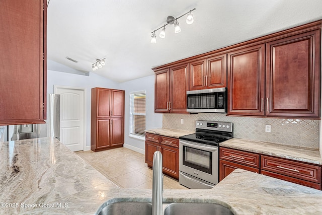 kitchen with light stone counters, sink, vaulted ceiling, and stainless steel appliances