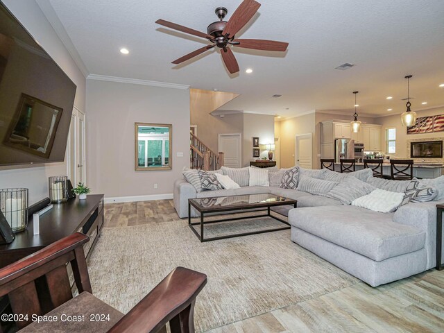 living room with light wood-type flooring, crown molding, and ceiling fan