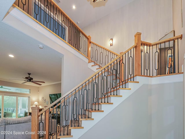 stairs featuring a towering ceiling and ceiling fan