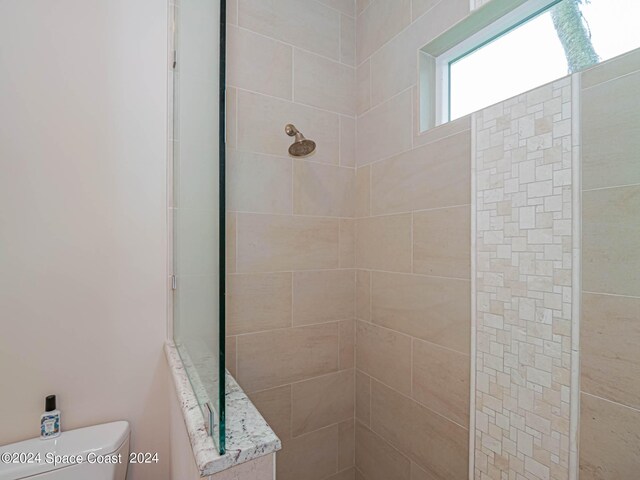 bathroom with tiled shower and toilet