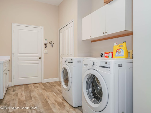 washroom featuring washing machine and dryer, light hardwood / wood-style flooring, and cabinets