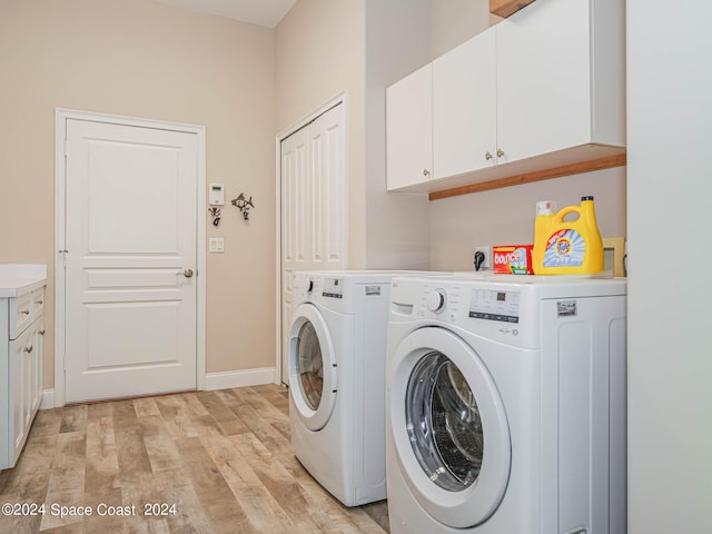 clothes washing area featuring cabinets, light wood-type flooring, and washing machine and clothes dryer