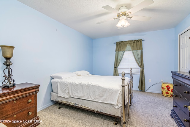 bedroom with a textured ceiling, ceiling fan, and light carpet