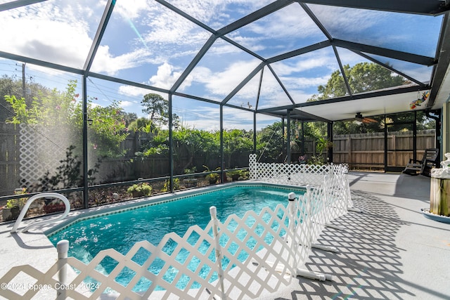 view of swimming pool featuring pool water feature, ceiling fan, a patio, and glass enclosure