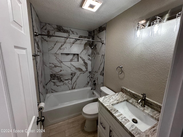 full bathroom with vanity, tiled shower / bath combo, a textured ceiling, and toilet