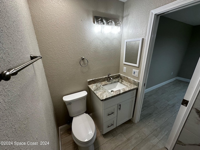 bathroom featuring toilet, vanity, and hardwood / wood-style flooring