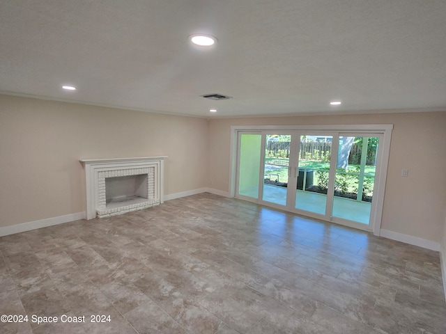 unfurnished living room with a brick fireplace, tile patterned floors, and crown molding