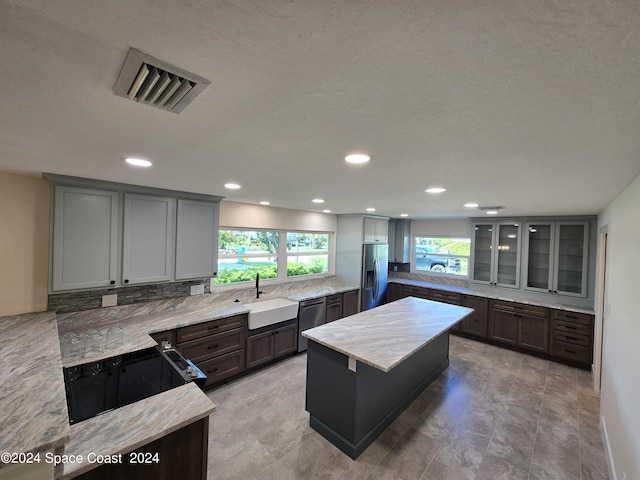 kitchen featuring stainless steel appliances, plenty of natural light, a center island, and sink