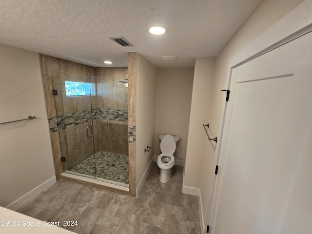 bathroom with walk in shower, toilet, and a textured ceiling