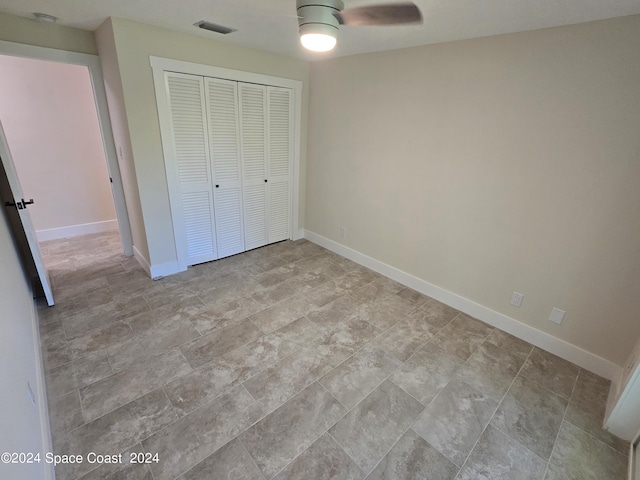 unfurnished bedroom with ceiling fan and a closet