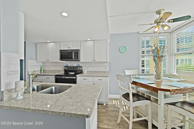 kitchen featuring white cabinets, ceiling fan, sink, and range with electric stovetop