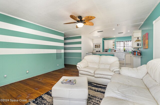 living room with dark wood-type flooring, ceiling fan, crown molding, and a textured ceiling