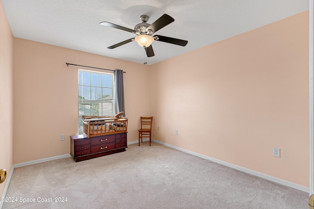 unfurnished room with ceiling fan, a textured ceiling, and light carpet