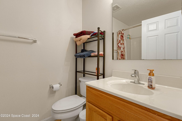 bathroom with a textured ceiling, toilet, and vanity