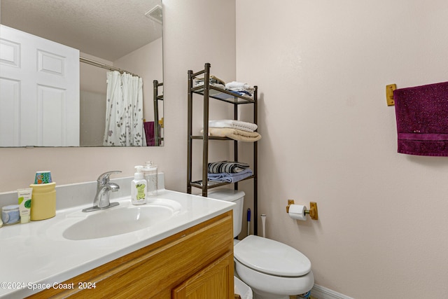 bathroom featuring a textured ceiling, toilet, and vanity