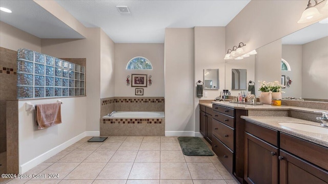 bathroom with vanity, a relaxing tiled tub, and tile patterned flooring