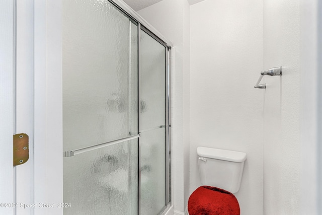 bathroom featuring toilet and a shower with shower door