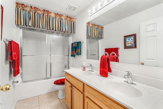 full bathroom featuring vanity, a textured ceiling, shower / bath combination with glass door, tile patterned flooring, and toilet