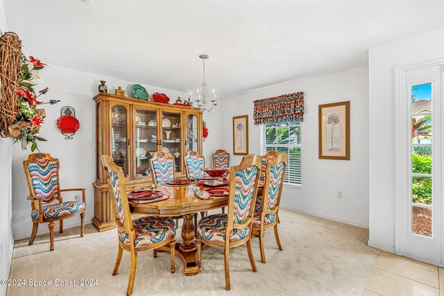 dining space with light colored carpet and an inviting chandelier