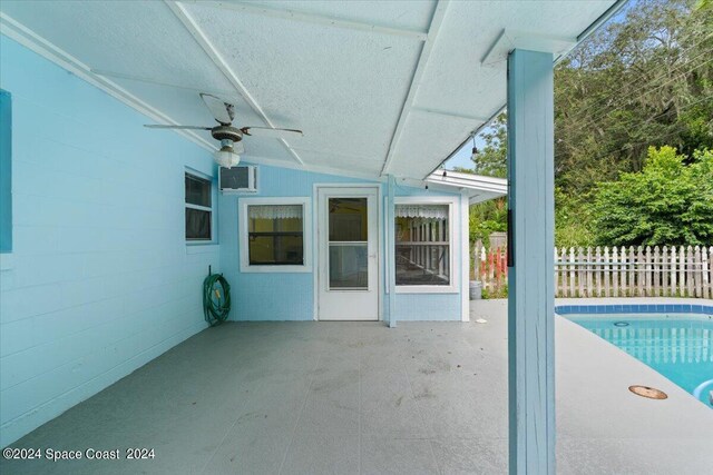 exterior space with a fenced in pool, ceiling fan, fence, an AC wall unit, and a patio area