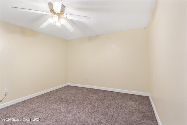 carpeted empty room featuring a ceiling fan and baseboards