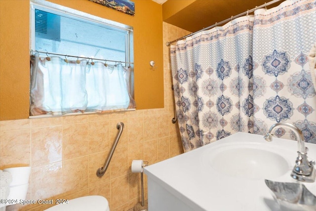 full bathroom with curtained shower, a sink, tile walls, and toilet