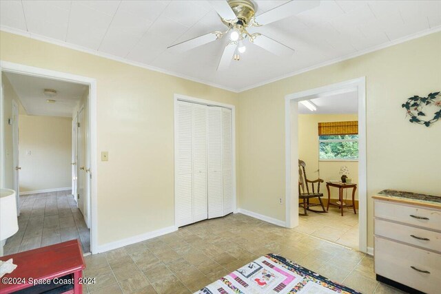 tiled bedroom featuring ceiling fan, ornamental molding, and a closet