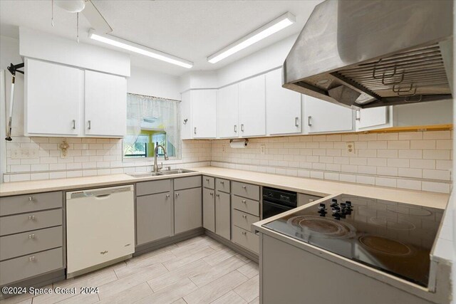 kitchen with backsplash, gray cabinets, wall chimney exhaust hood, white dishwasher, and sink