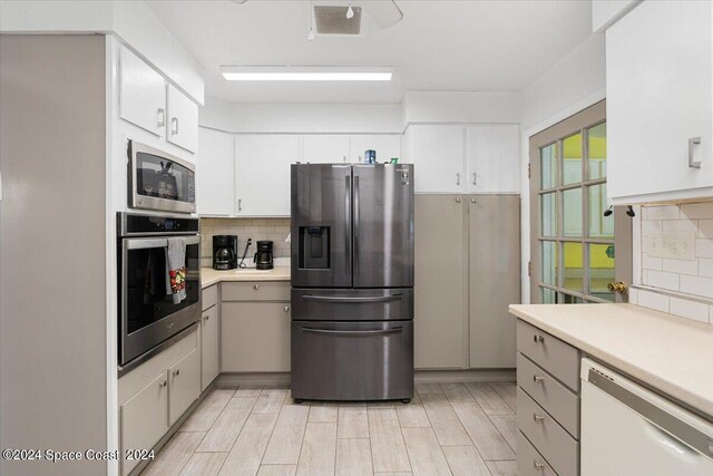 kitchen featuring decorative backsplash, white cabinetry, appliances with stainless steel finishes, and light hardwood / wood-style floors