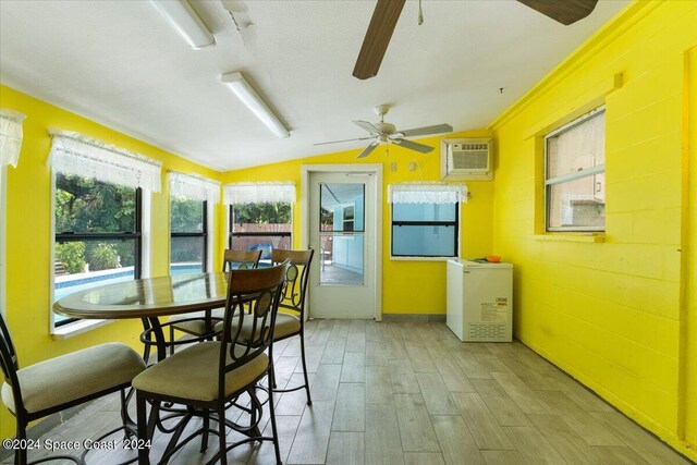 sunroom / solarium featuring ceiling fan, vaulted ceiling, and a wall mounted AC