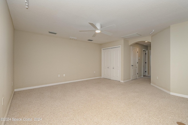 empty room featuring ceiling fan, light carpet, and a textured ceiling