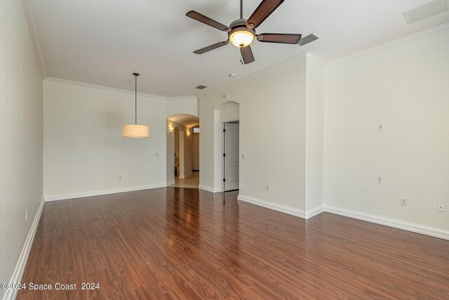 empty room with dark hardwood / wood-style flooring, ornamental molding, and ceiling fan