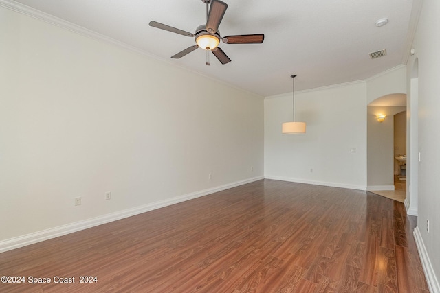 empty room featuring dark hardwood / wood-style flooring, ornamental molding, and ceiling fan