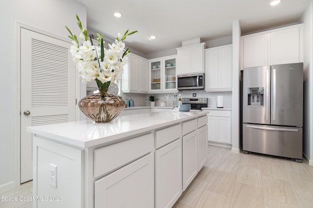 kitchen featuring white cabinetry, appliances with stainless steel finishes, a center island, and backsplash