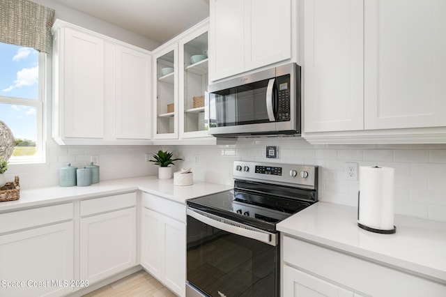 kitchen featuring stainless steel appliances, decorative backsplash, and white cabinets