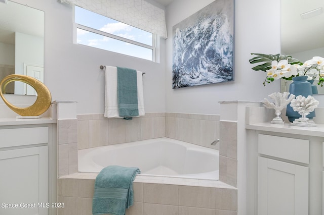 bathroom featuring vanity and tiled tub