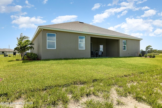 rear view of property featuring a yard and central air condition unit