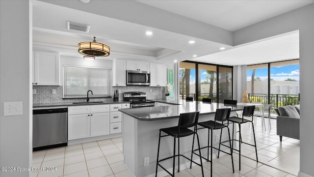 kitchen featuring appliances with stainless steel finishes, sink, white cabinetry, and decorative backsplash